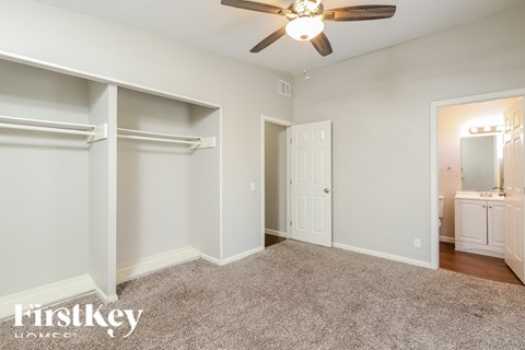 A bedroom with a ceiling fan and a carpeted floor.