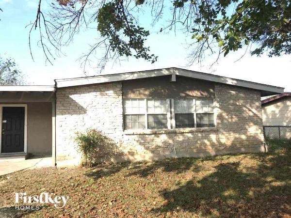 A house with a brick wall and a black door is for sale.