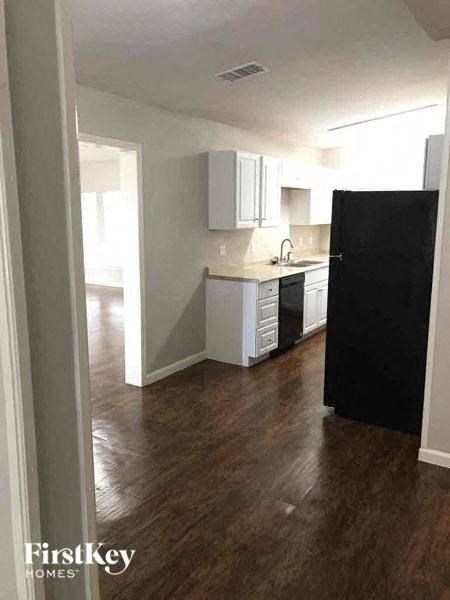 A kitchen with a black refrigerator and wooden floors.