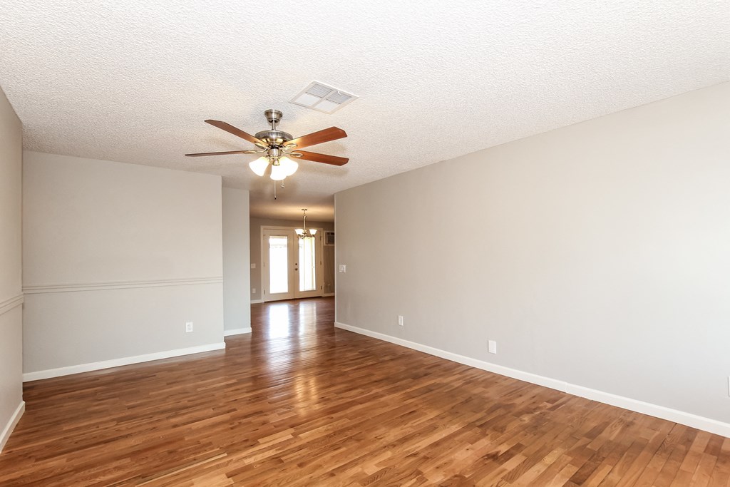 A room with a ceiling fan and wooden flooring.