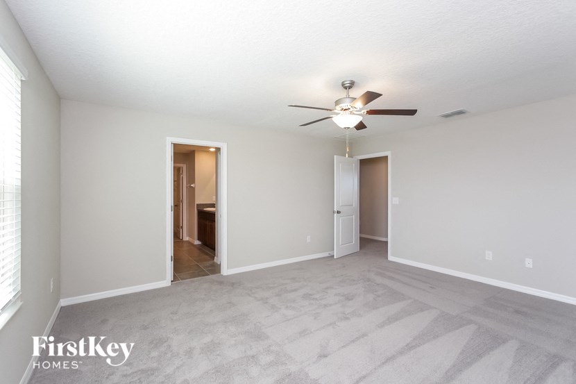 A spacious room with a ceiling fan and two doors.