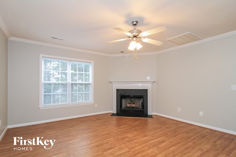 A spacious room with a fireplace and a ceiling fan.