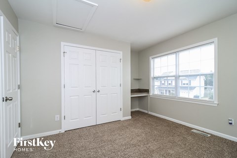 A bedroom with a carpeted floor and a window.