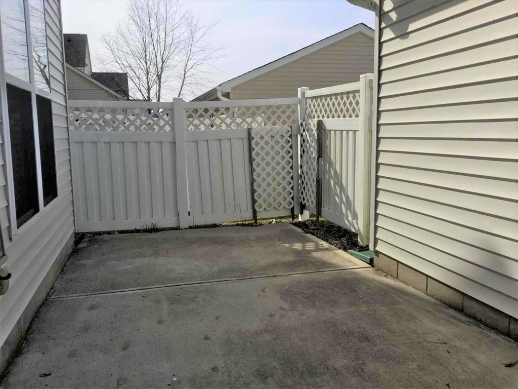 a white fence in front of a house with a driveway