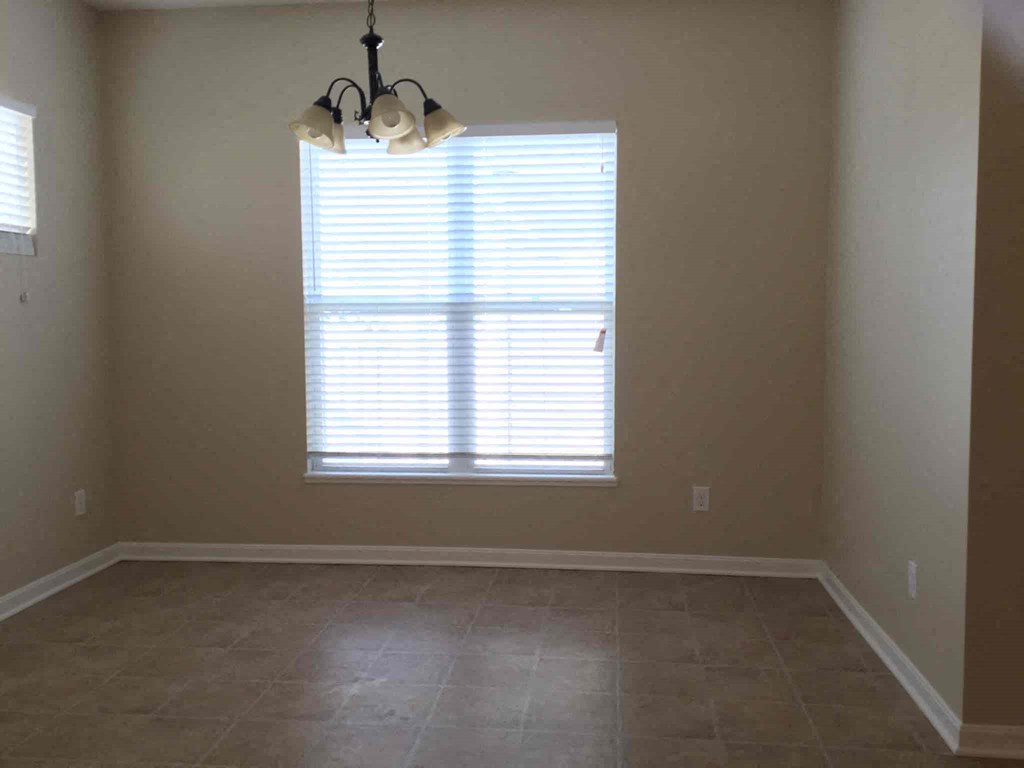 an empty living room with a large window and tiled floors