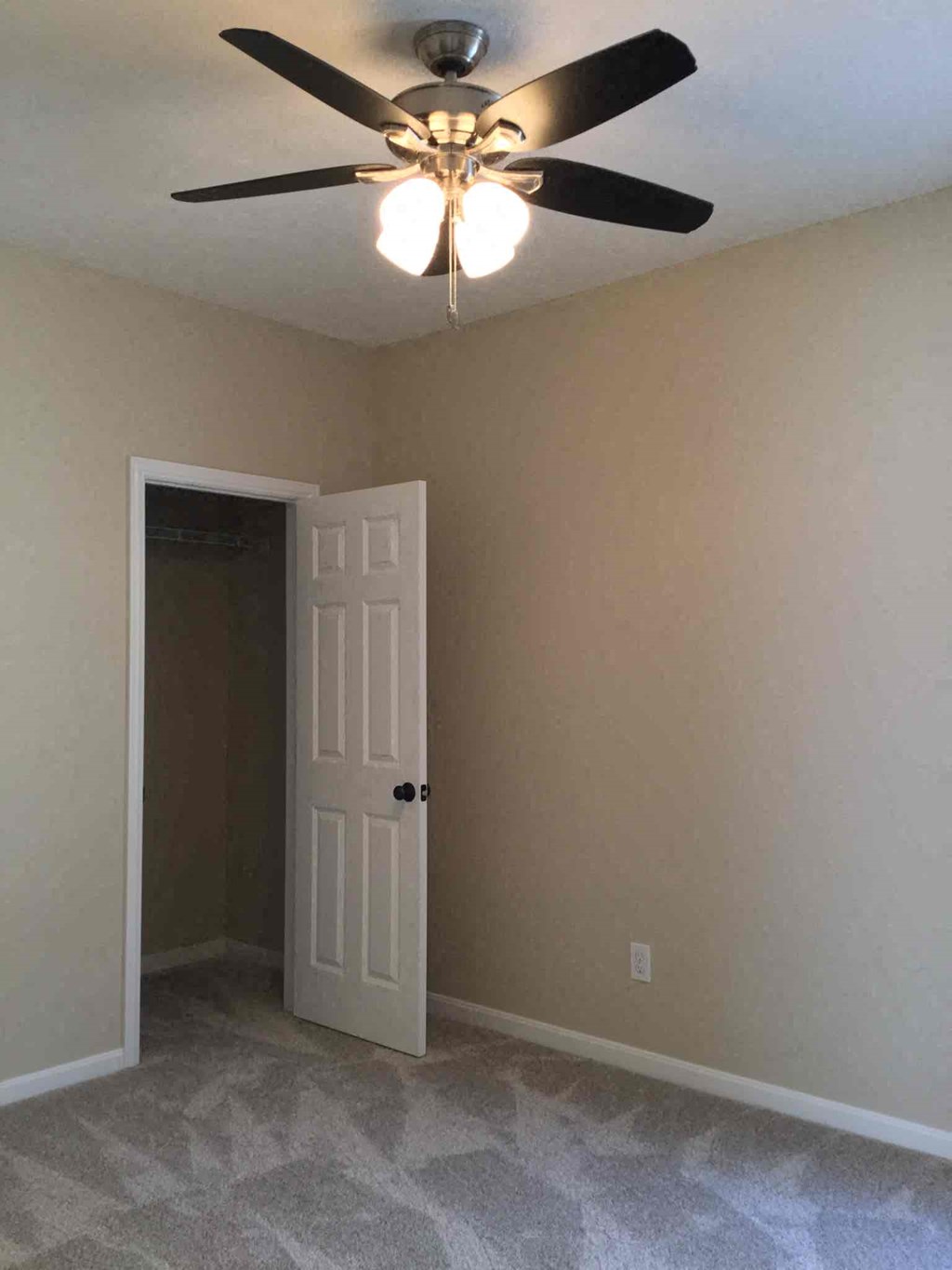 a bedroom with a ceiling fan and a door to a closet