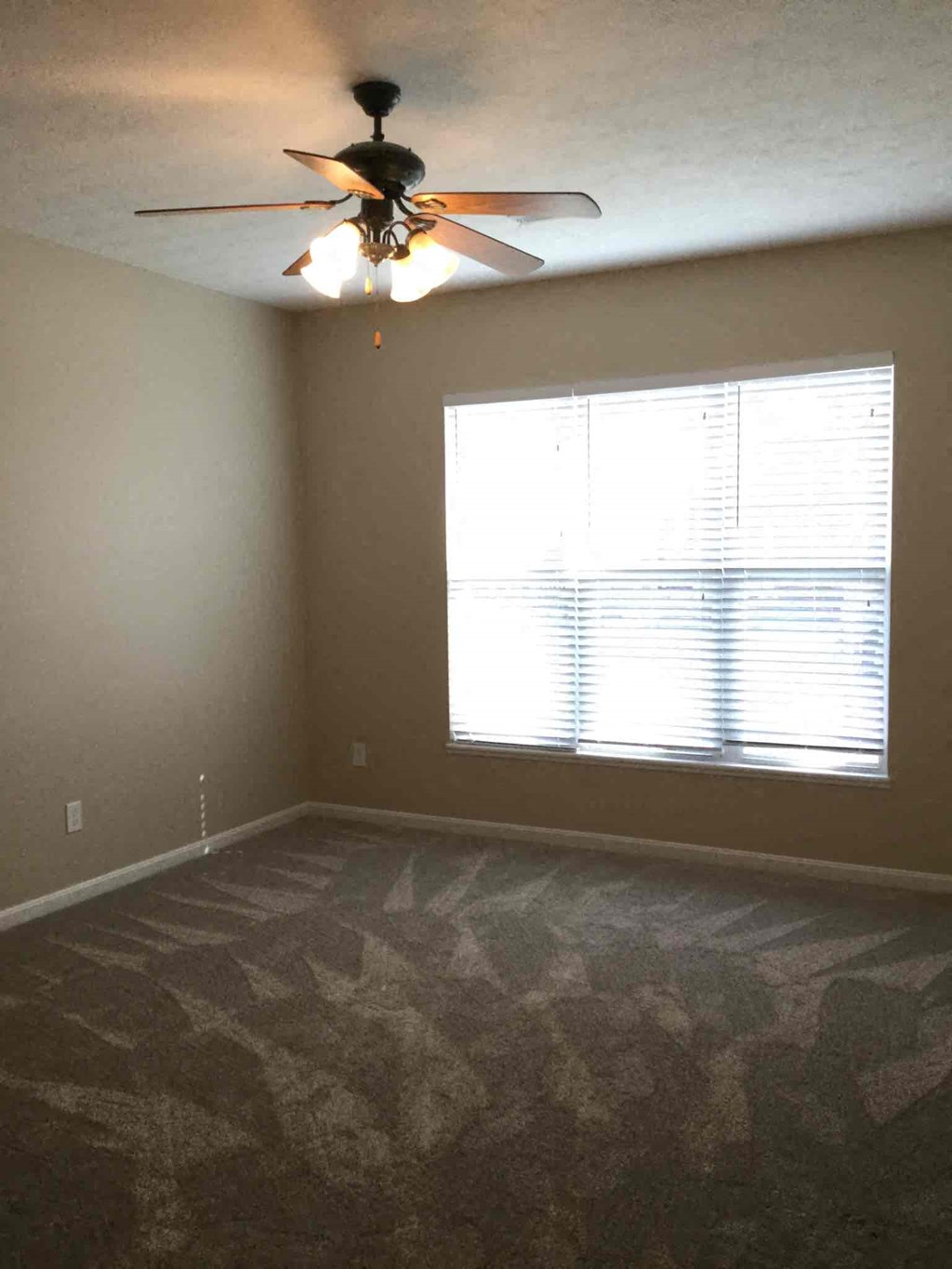 an empty room with a ceiling fan and a window