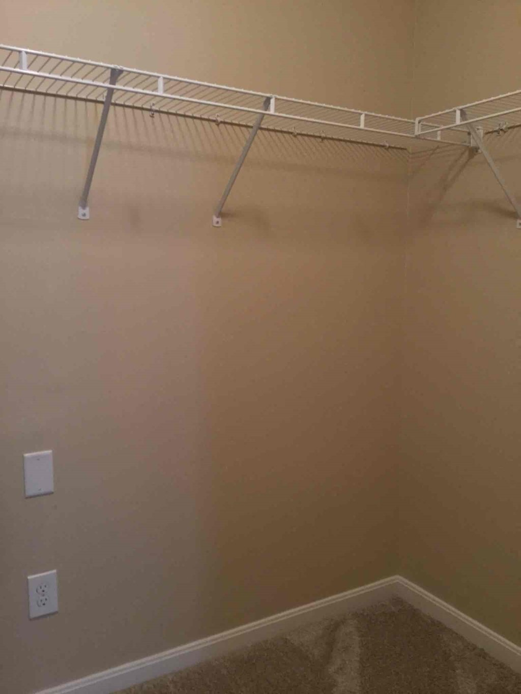 a walk in closet with a wire rack on the wall