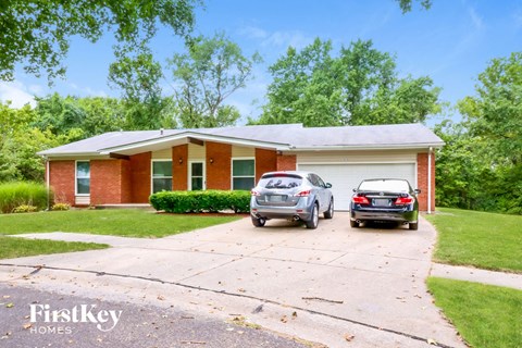 a small brick house with two cars parked in the driveway