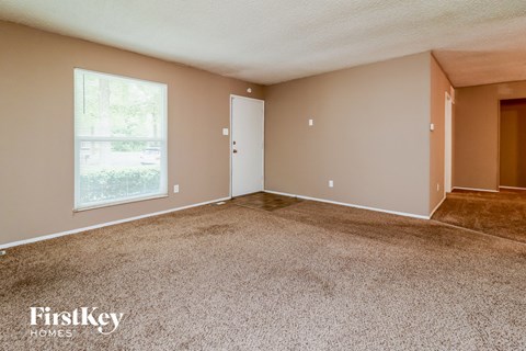an empty living room with carpet and a window