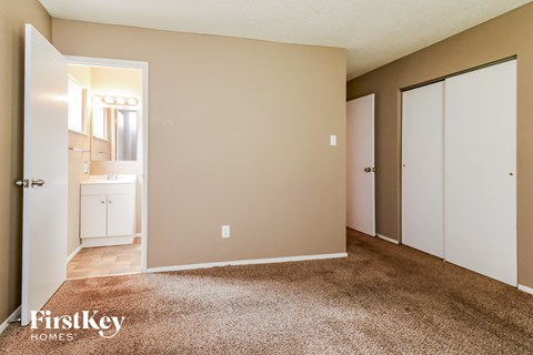 a bedroom with a carpeted floor and doors to a bathroom
