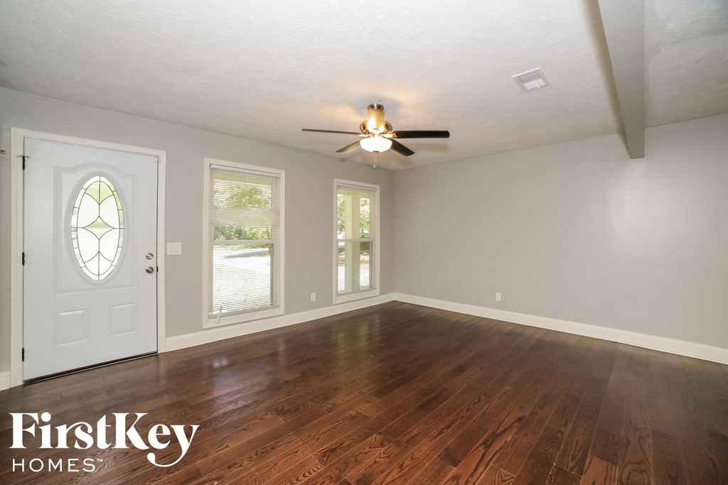 the living room of a house with wood floors and a ceiling fan