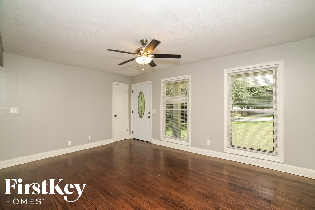 the living room of an empty house with a ceiling fan