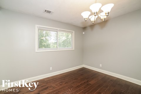 a bedroom with hardwood flooring and a window and a chandelier