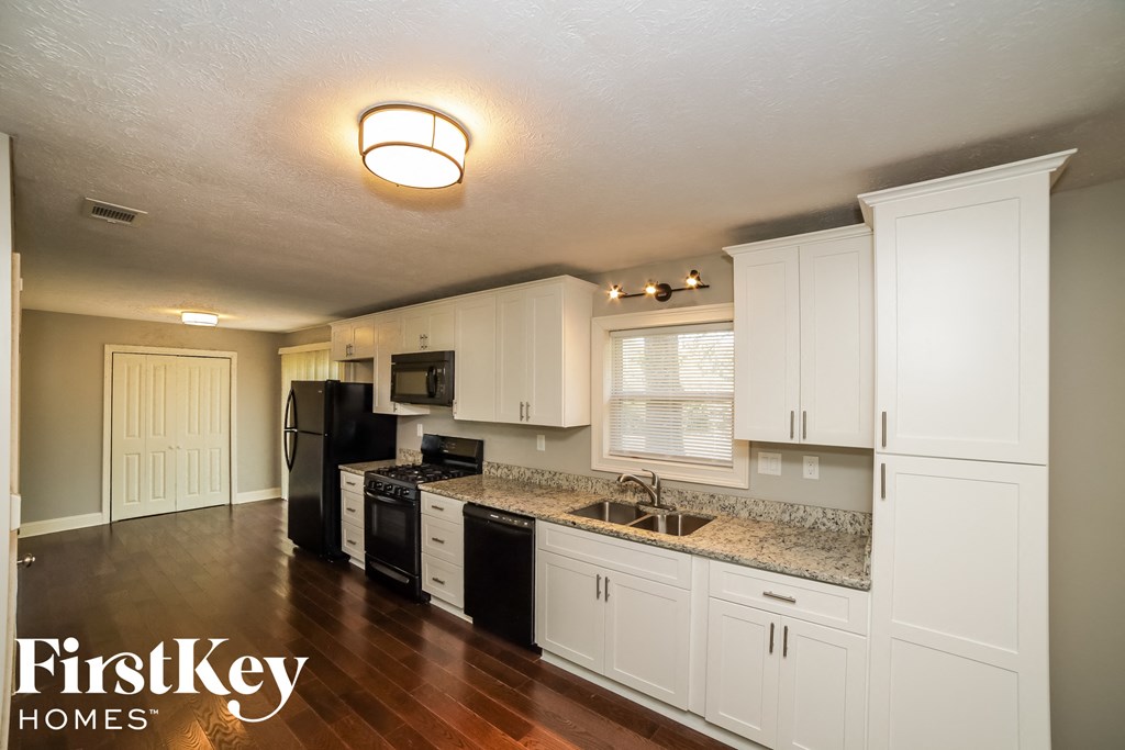 a kitchen with white cabinets and granite counter tops and black appliances