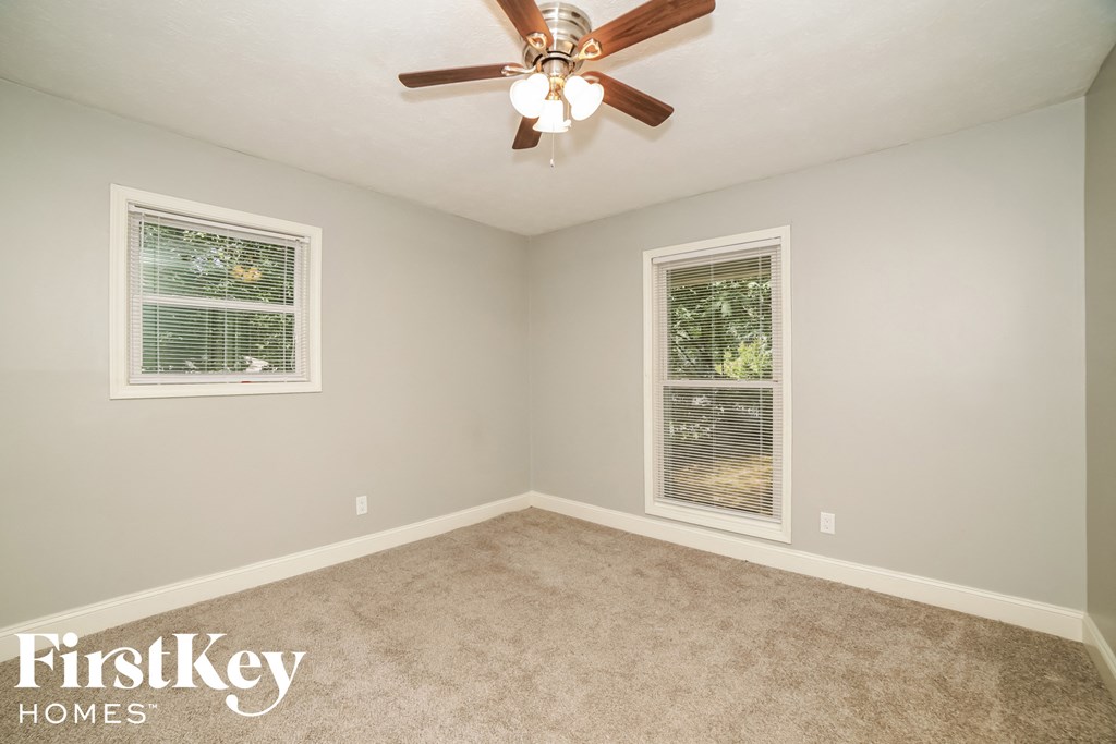 a bedroom with a ceiling fan and two windows