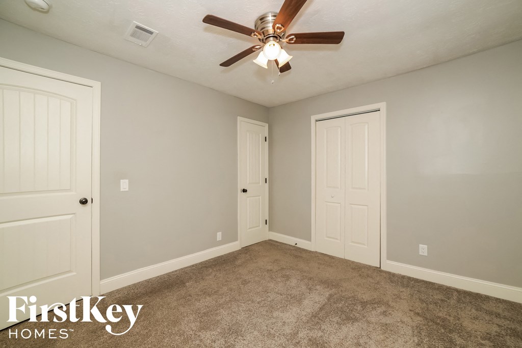 a bedroom with two doors and a ceiling fan