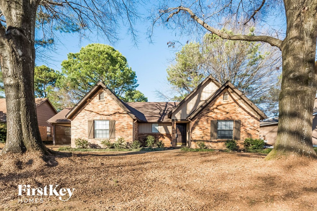 A brick house with trees in front of it.