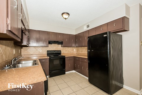 A kitchen with a black fridge and a stove top oven.