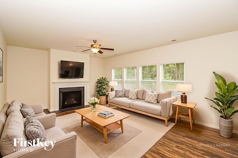 A living room with a fireplace, a couch, a chair, a coffee table, and a potted plant.