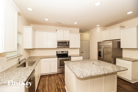 A kitchen with white cabinets and granite countertops.