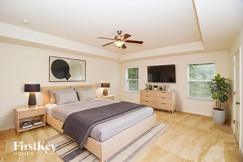 A bedroom with a bed, nightstands, and a ceiling fan.