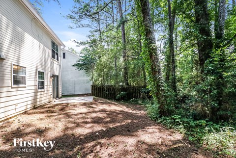 a backyard with trees and a white house