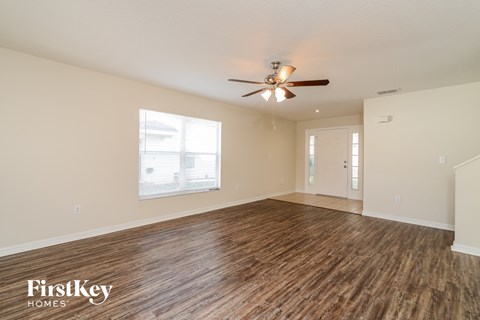 A spacious room with wooden flooring and a ceiling fan.