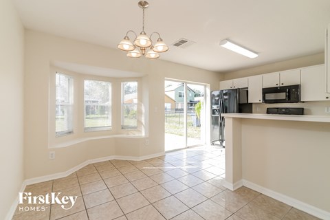 A kitchen area with a black fridge and microwave, a chandelier, and a sliding glass door leading to a backyard.