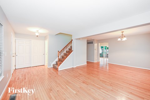 A spacious room with wooden flooring and a staircase leading to the upper level.