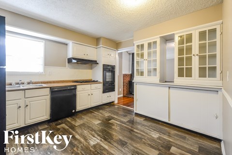a kitchen with white cabinets and black appliances and wood floors