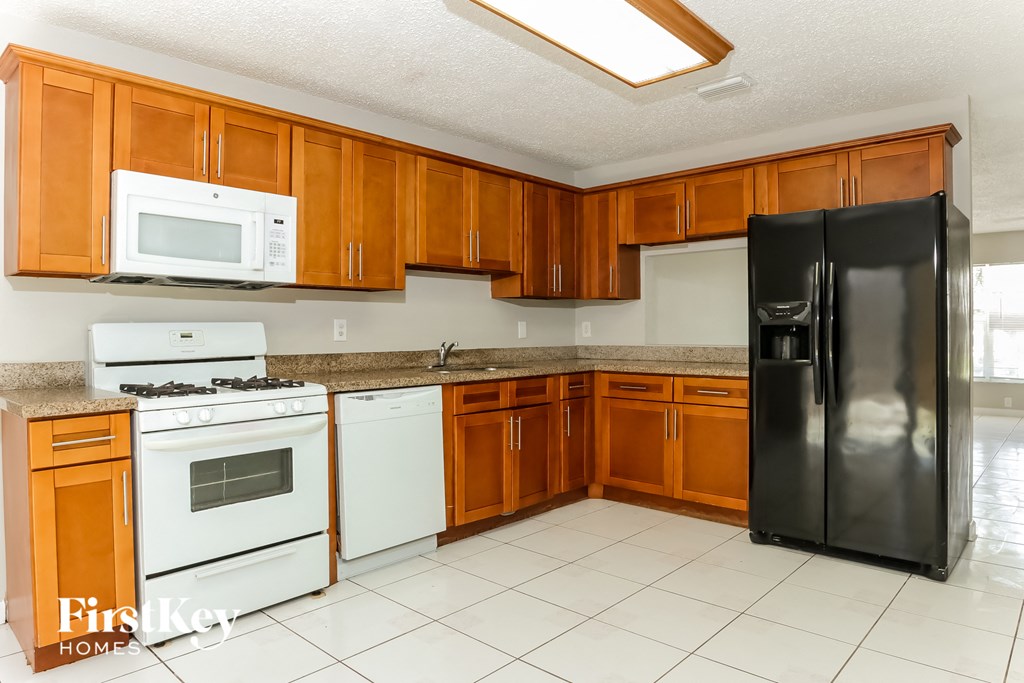 A kitchen with wooden cabinets and a black refrigerator.