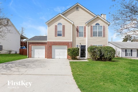 a beige house with two garage doors and a driveway