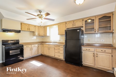 a kitchen with wooden cabinets and black appliances and a ceiling fan