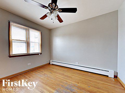 an empty living room with wood floors and a ceiling fan