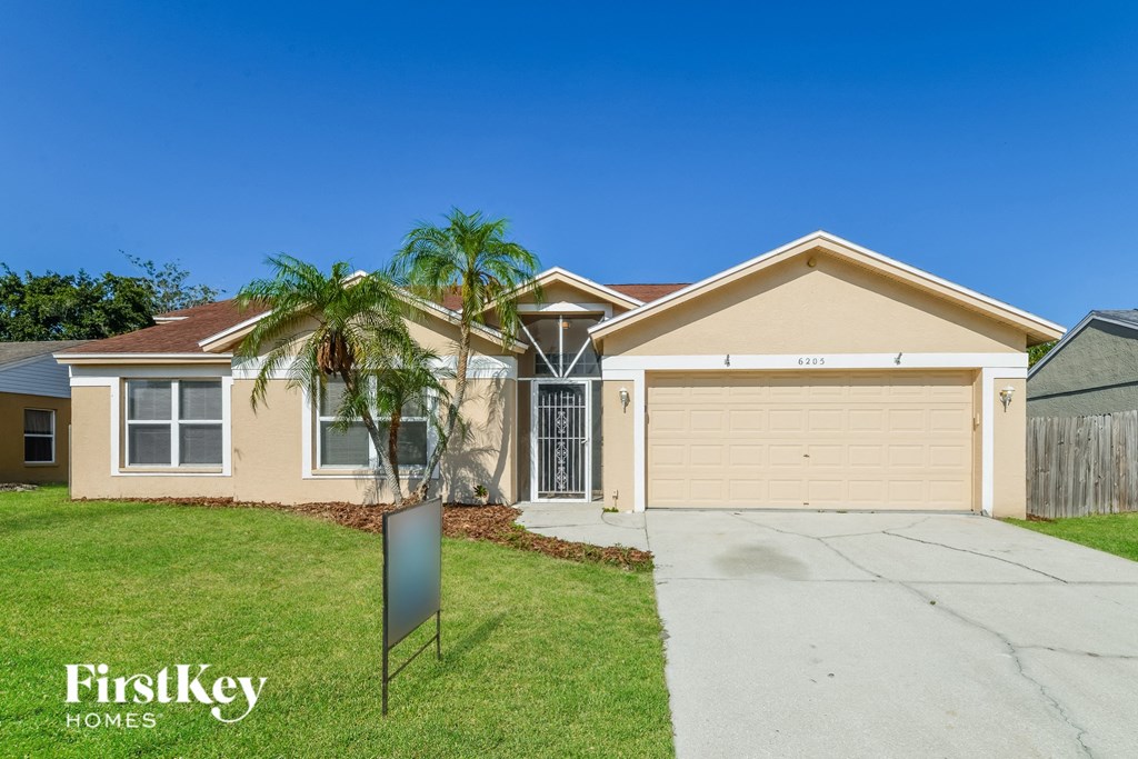 a beige house with a garage and palm trees
