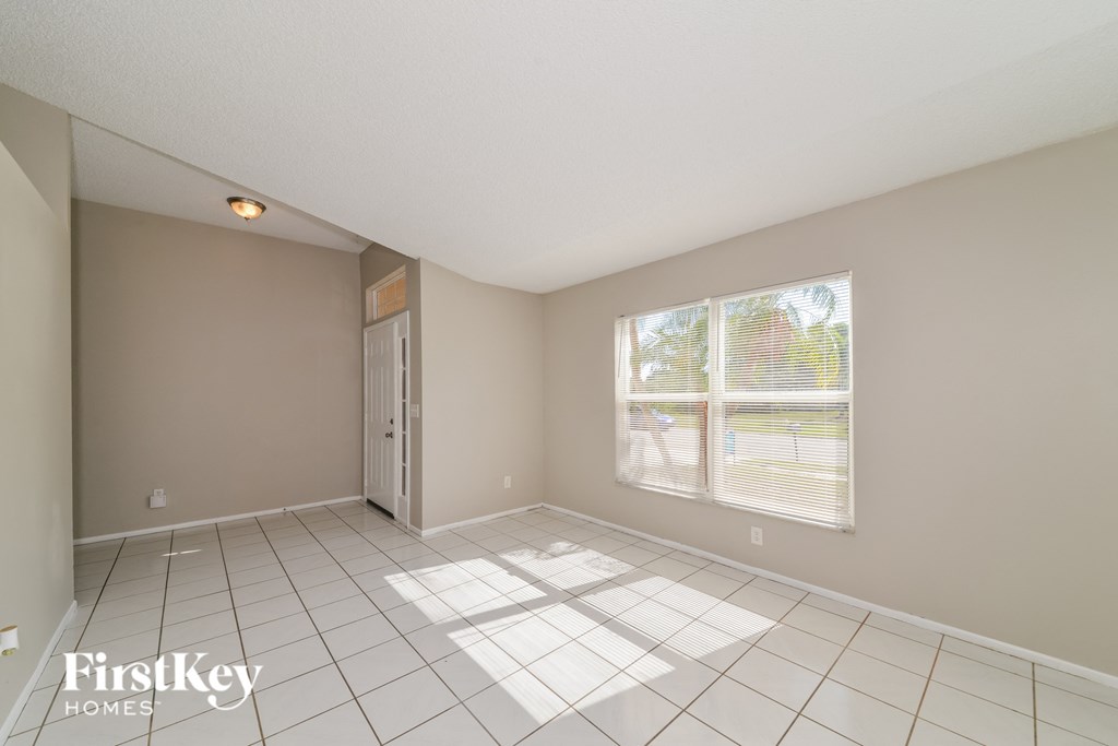 a spacious living room with a large window and a tiled floor