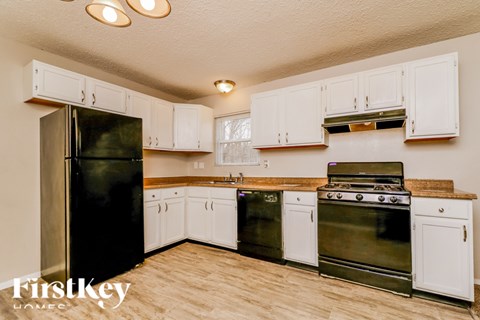 A kitchen with white cabinets and a black refrigerator.