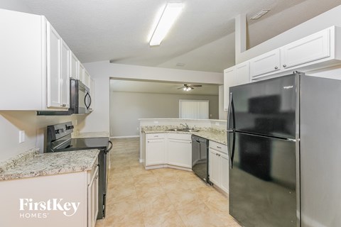 A kitchen with a refrigerator, microwave, and oven.