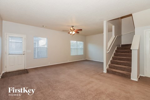 A spacious room with a staircase and a ceiling fan.