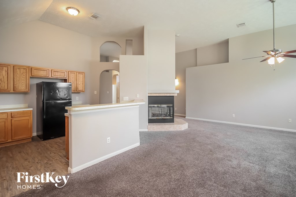 the living room and kitchen of an empty house with a carpeted floor