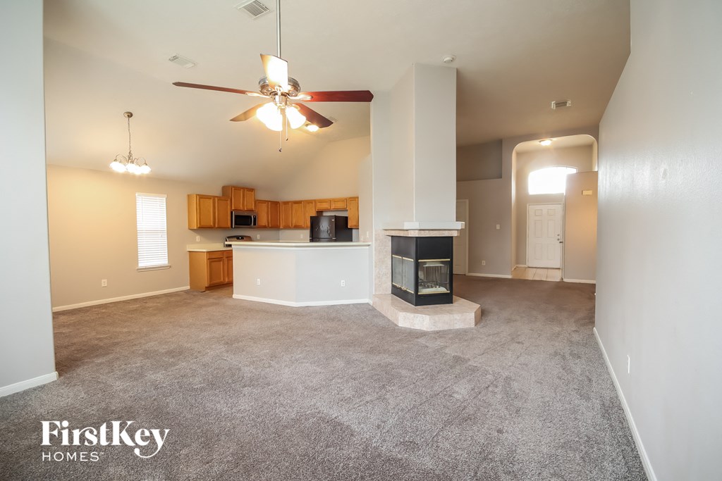 an empty living room with a fireplace and a kitchen