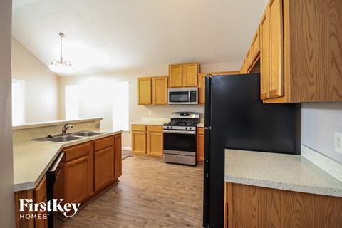 a kitchen with wooden cabinets and a black refrigerator