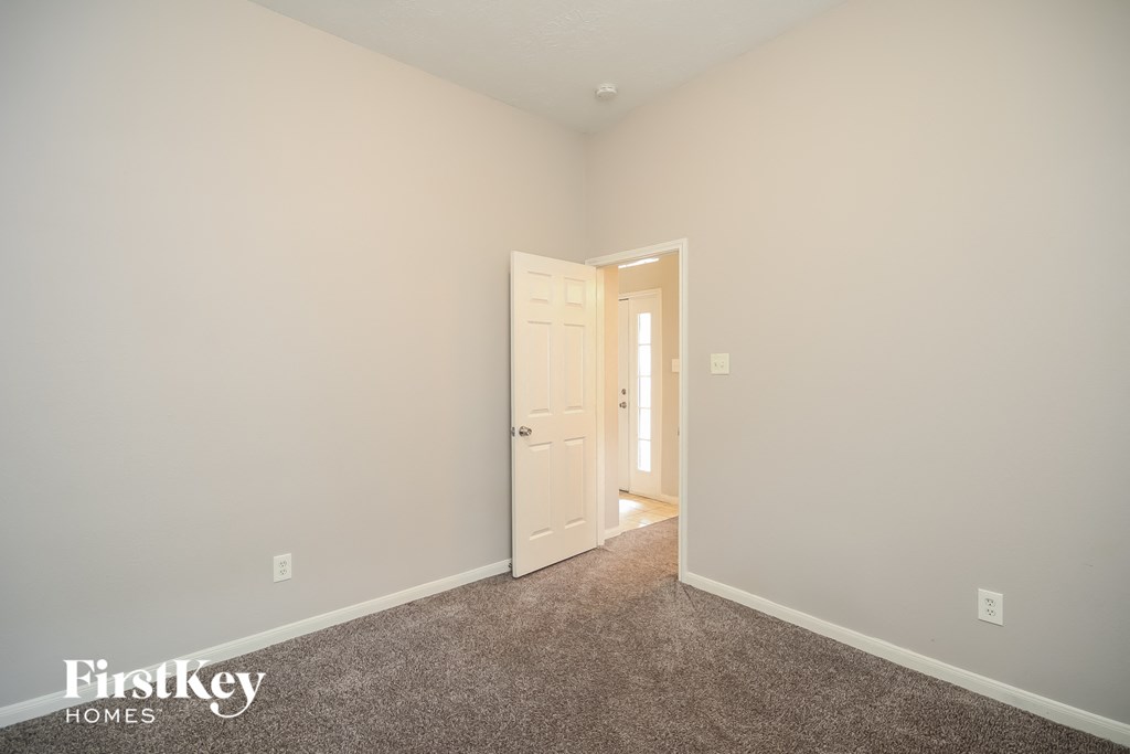 a bedroom with white walls and carpet and a door to a closet