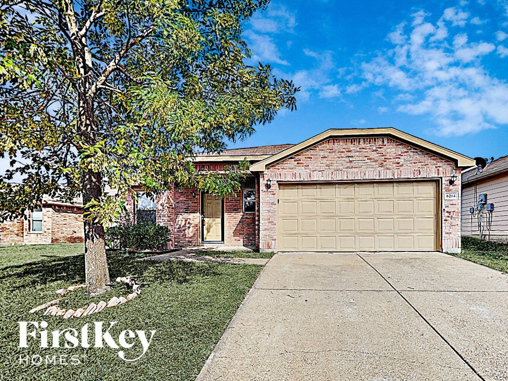 A house with a garage door and a tree in front of it.