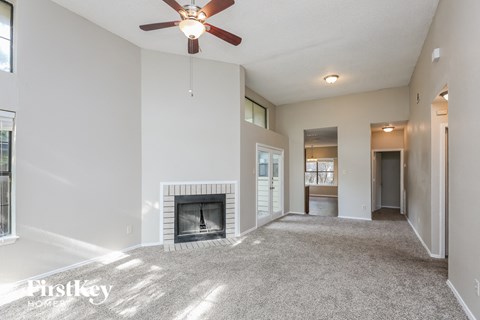 A spacious living room with a fireplace and a ceiling fan.