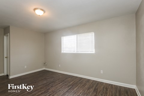 the spacious living room with wood flooring and a window