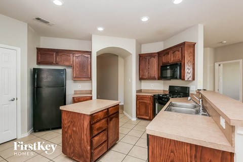 A kitchen with wooden cabinets and a black refrigerator.