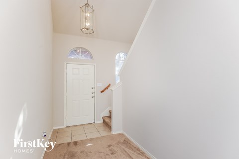 a entryway with a white door and a carpeted staircase