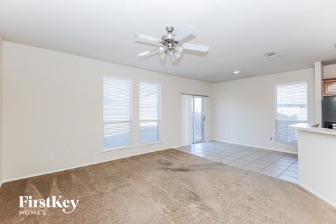an empty living room with a ceiling fan and a window